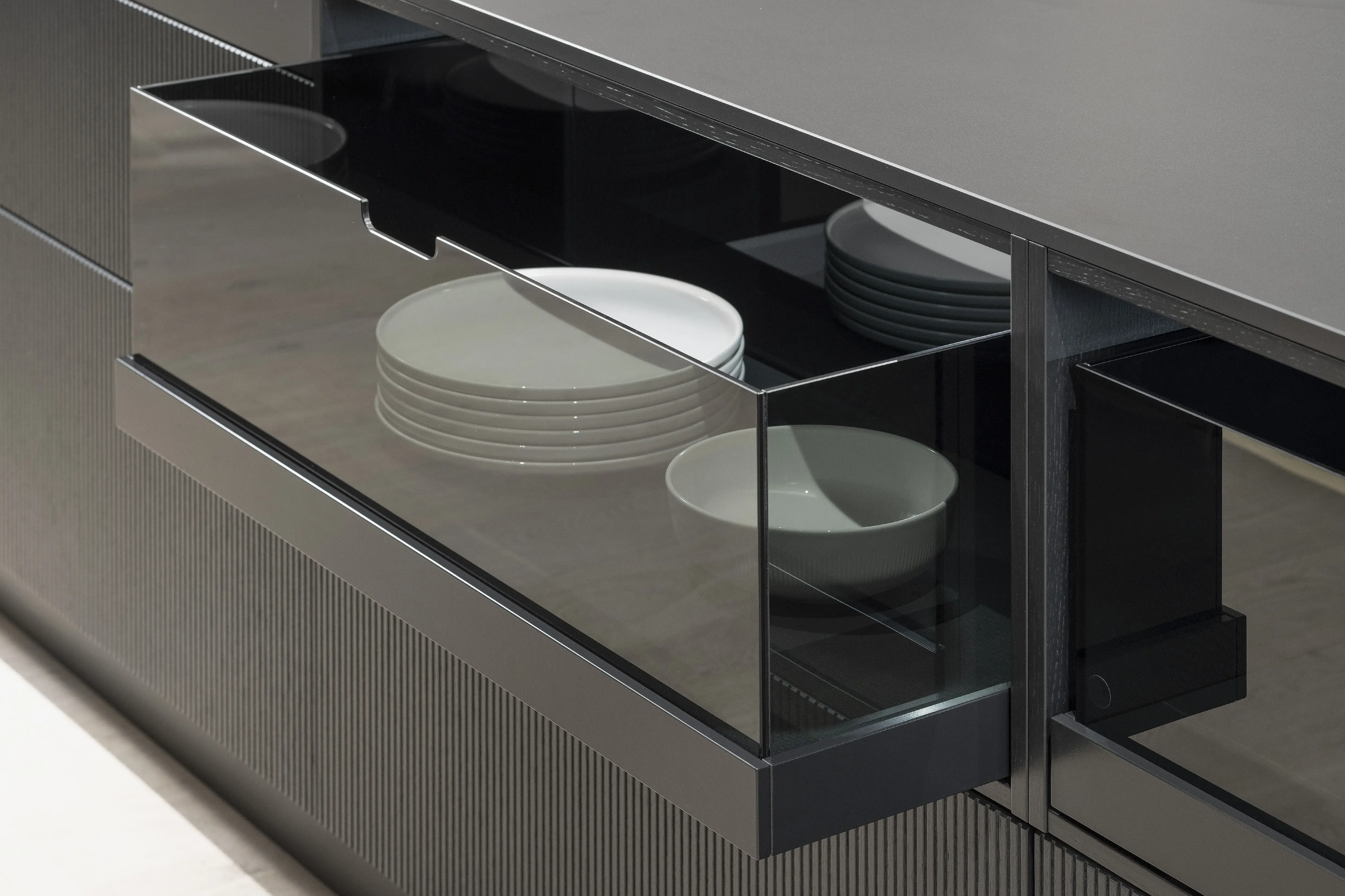 APL: Silk Negro Naturale (Keramik) 16 mm   Front: AV 6023-GL Eiche-schwarz Echtholzfurnier Rille AV 7070 Industriestahl Bronze, Metalliclack Korpus: 4059 Titan Griff: Kehlleiste 355 Schwarz matt Geräte: Miele Armatur: Gessi Features: Regalwandlösung mit beleuchtetem Wandboard, Oberfläche von Hand bearbeitet, Materialmix, Trendthema Bronze, Glasschublade mit Plexiglas in Schwarz getönt, Thekenlösung mittig, Wand aus Oberflächenmaterial in Bronze mit beleuchteten Funktionsleisten für Gläser, etc. 